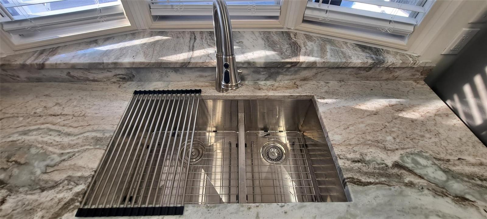 A stainless steel double-basin kitchen sink is set into a marble countertop with a faucet — 5362 SE 65th Avenue, Okeechobee FL 34974, OKEECHOBEE, FL