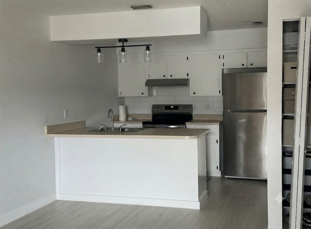 A kitchen features white cabinets, a stainless steel refrigerator, a breakfast bar, and light flooring — 5355 SE 29TH PLACE, OCALA, FL