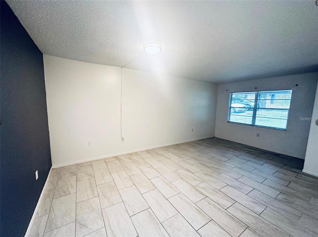 An empty room features white walls, a dark accent wall, and light-colored tile flooring — 101 LAKE HUNTER DRIVE UNIT 15 & 16, LAKELAND, FL