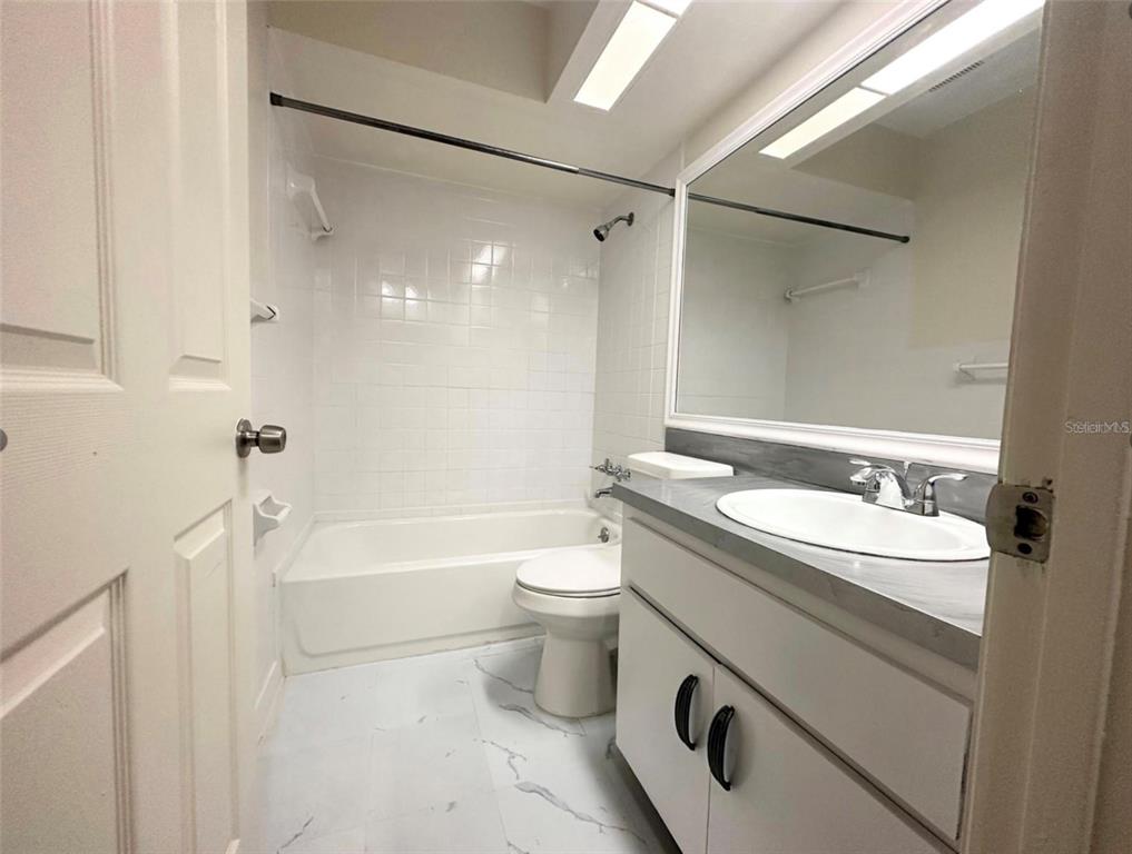 A bathroom features a white vanity, a toilet, and a shower-tub combination with white tile — 101 LAKE HUNTER DRIVE UNIT 15 & 16, LAKELAND, FL