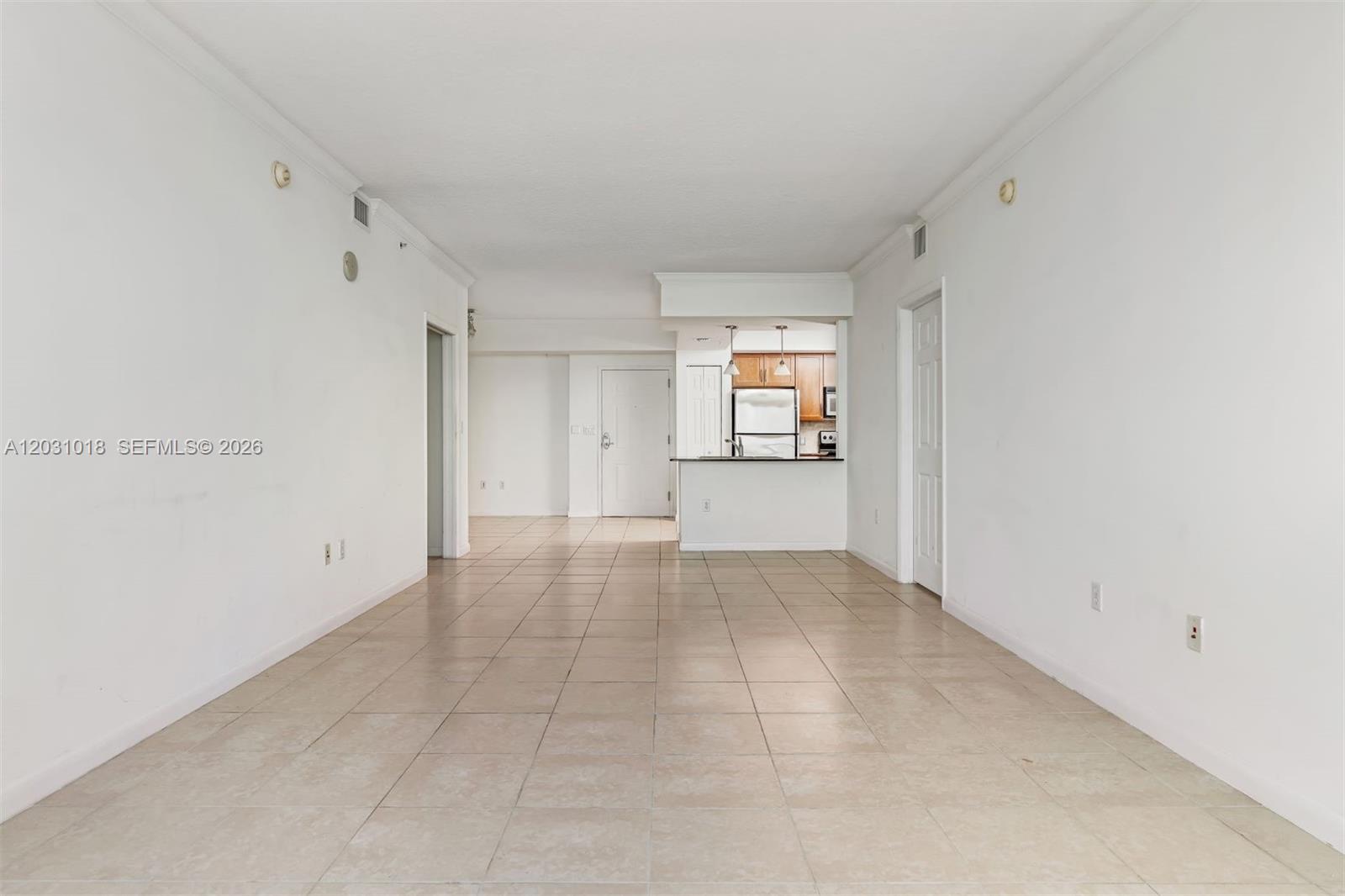 An empty living area features white walls, beige tile flooring, and an open kitchen — 2000 N Bayshore Dr # 420, Miami FL 33137, MIAMI, FL