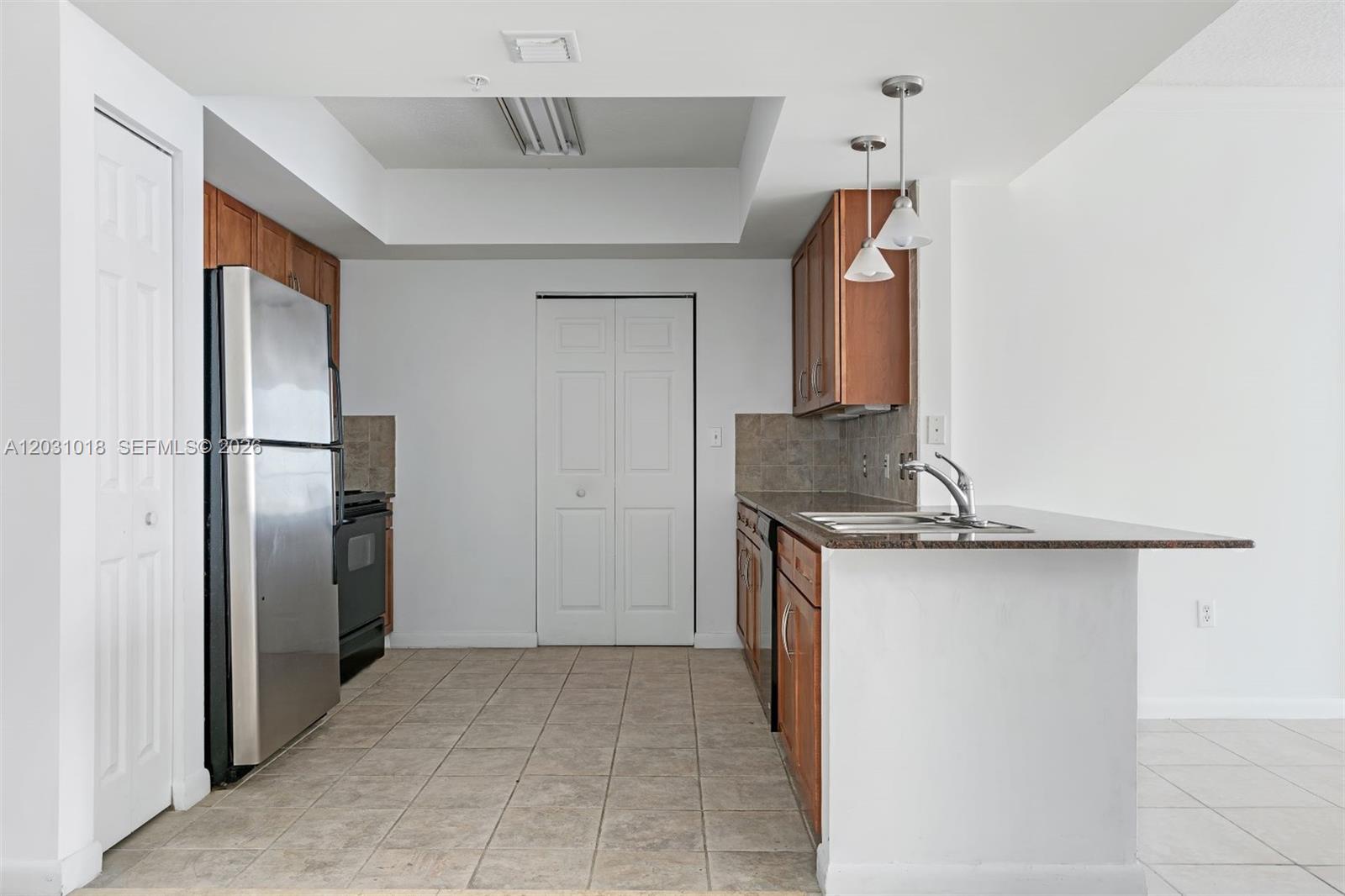 A kitchen features stainless steel appliances, wood cabinets, granite countertops, and tile flooring — 2000 N Bayshore Dr # 420, Miami FL 33137, MIAMI, FL
