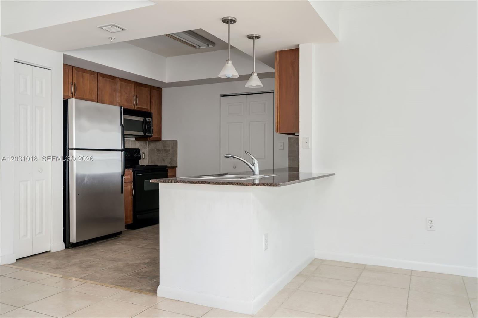 A kitchen features wood cabinets, stainless steel appliances, a breakfast bar, and tile flooring — 2000 N Bayshore Dr # 420, Miami FL 33137, MIAMI, FL
