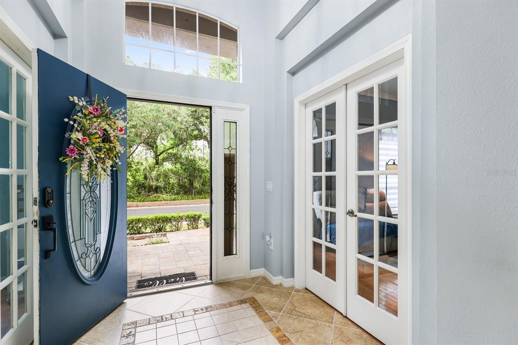 A hallway with tile flooring leads toward a living area with glass French doors nearby — 12114 CREEK EDGE DRIVE, RIVERVIEW, FL