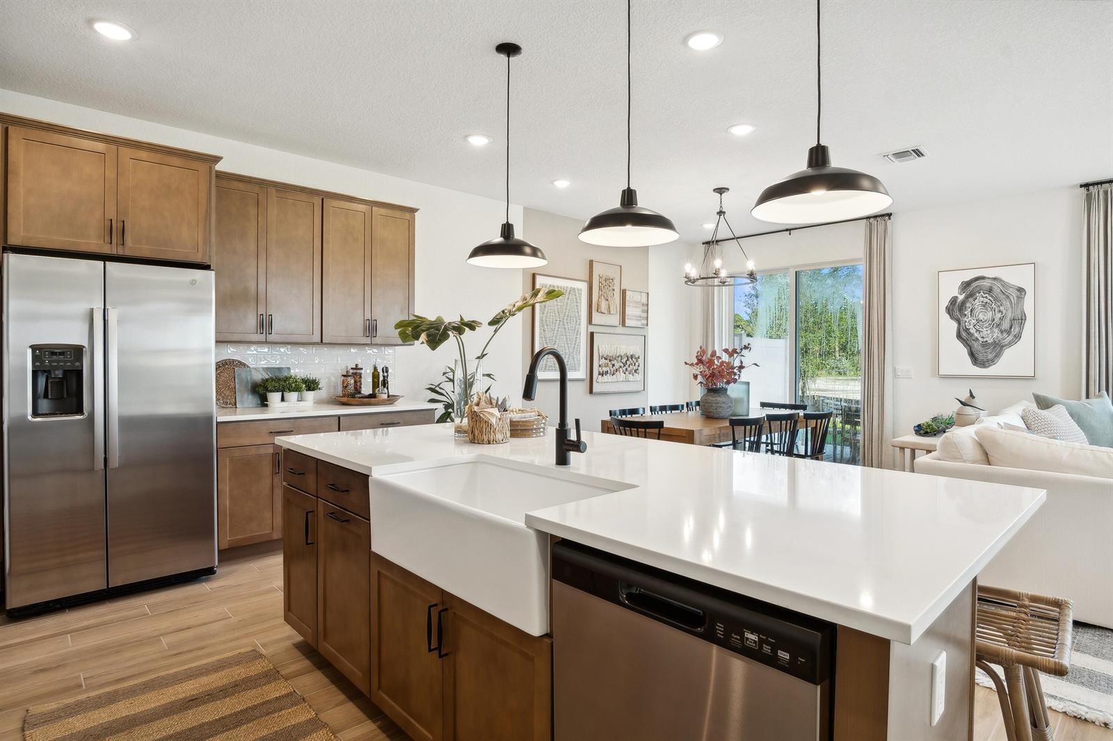 A kitchen features wood cabinets, a white farmhouse sink, and a large quartz island — 207 SE Birch Terrace, Stuart FL 34997, STUART, FL