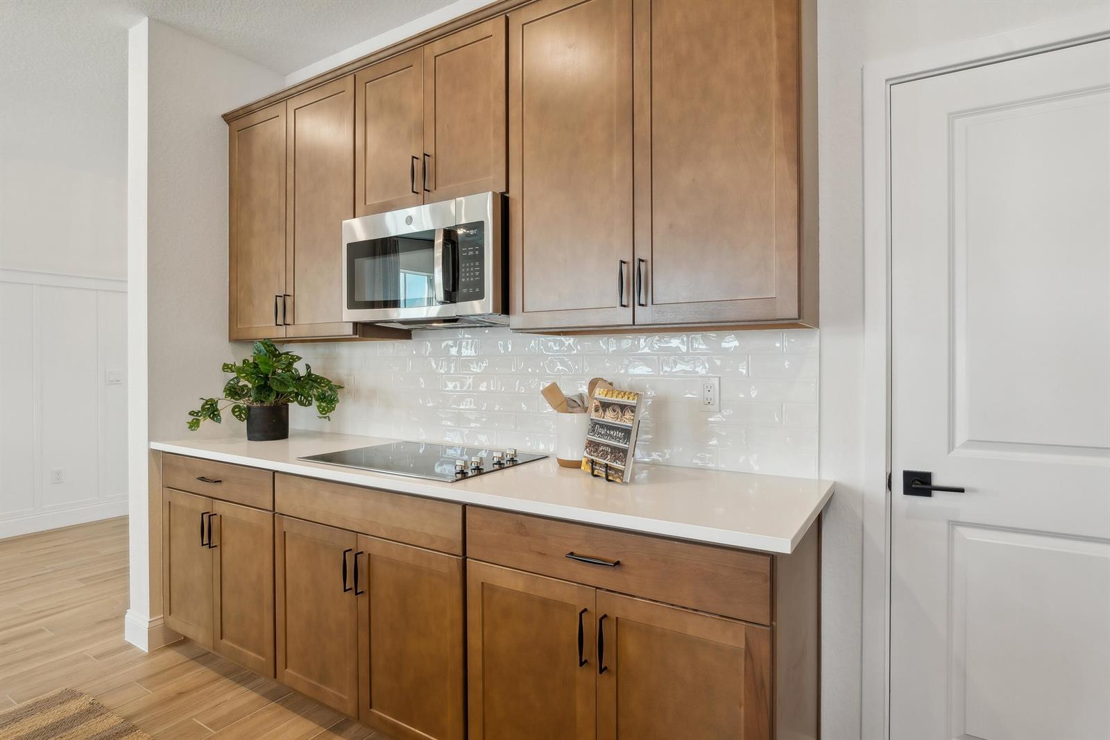 A kitchen features wood cabinets, a white countertop, a glass cooktop, and a subway tile backsplash — 207 SE Birch Terrace, Stuart FL 34997, STUART, FL