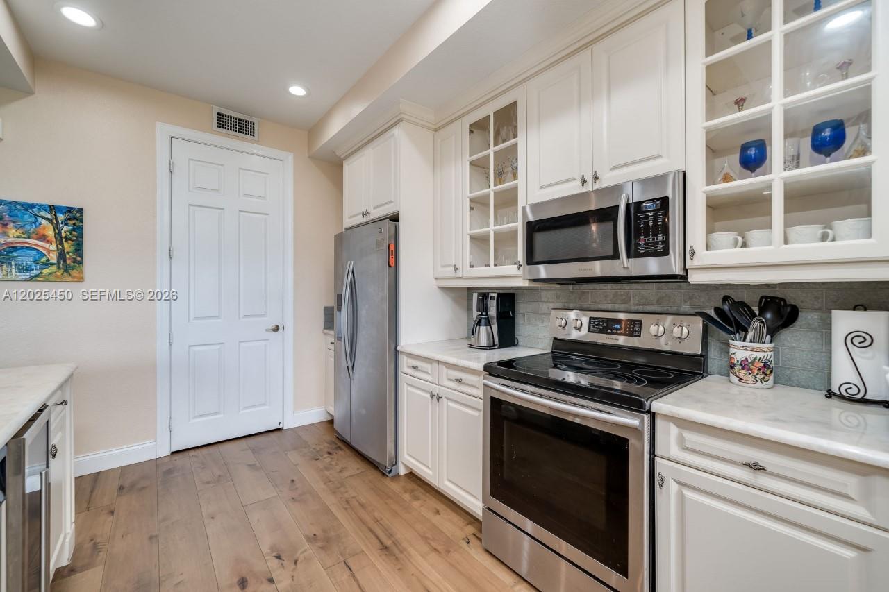 A kitchen features white cabinets, stainless steel appliances, and light-colored countertops — 8345 NW 128th Ln # A, Parkland FL 33076, PARKLAND, FL