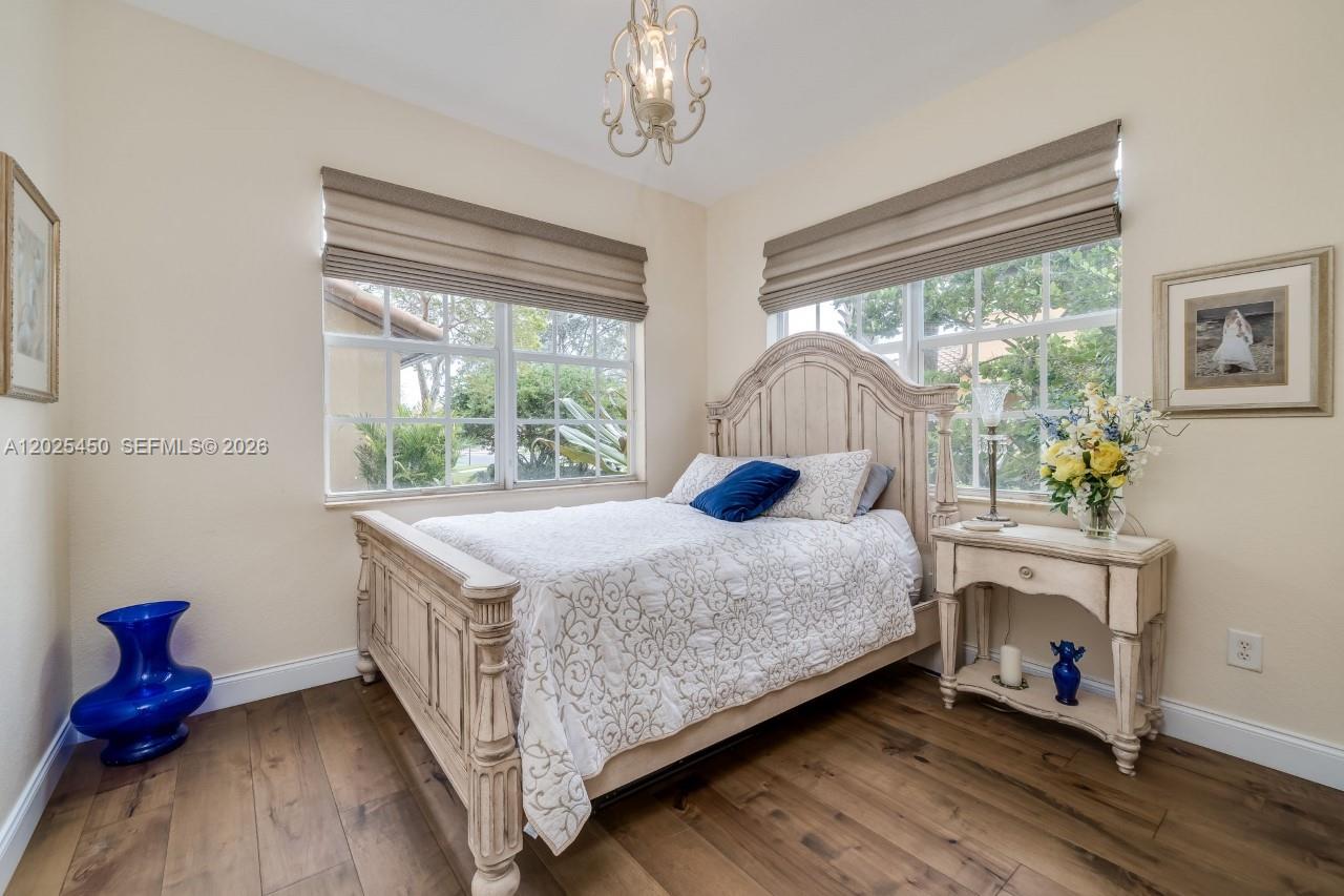 A bedroom features a wooden bed frame, light-colored walls, wood flooring, and two windows — 8345 NW 128th Ln # A, Parkland FL 33076, PARKLAND, FL