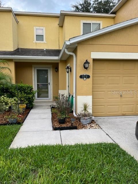 The exterior of a two-story yellow house features a front door, garage, and landscaped yard — 523 MOUNT OLYMPUS BOULEVARD, NEW SMYRNA BEACH, FL
