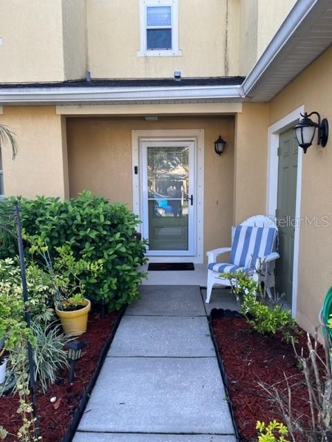 A concrete walkway leads to a front door with a white chair on the porch — 523 MOUNT OLYMPUS BOULEVARD, NEW SMYRNA BEACH, FL