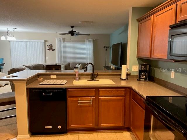 A kitchen with wood cabinets, a black dishwasher, and a view into the living room — 523 MOUNT OLYMPUS BOULEVARD, NEW SMYRNA BEACH, FL