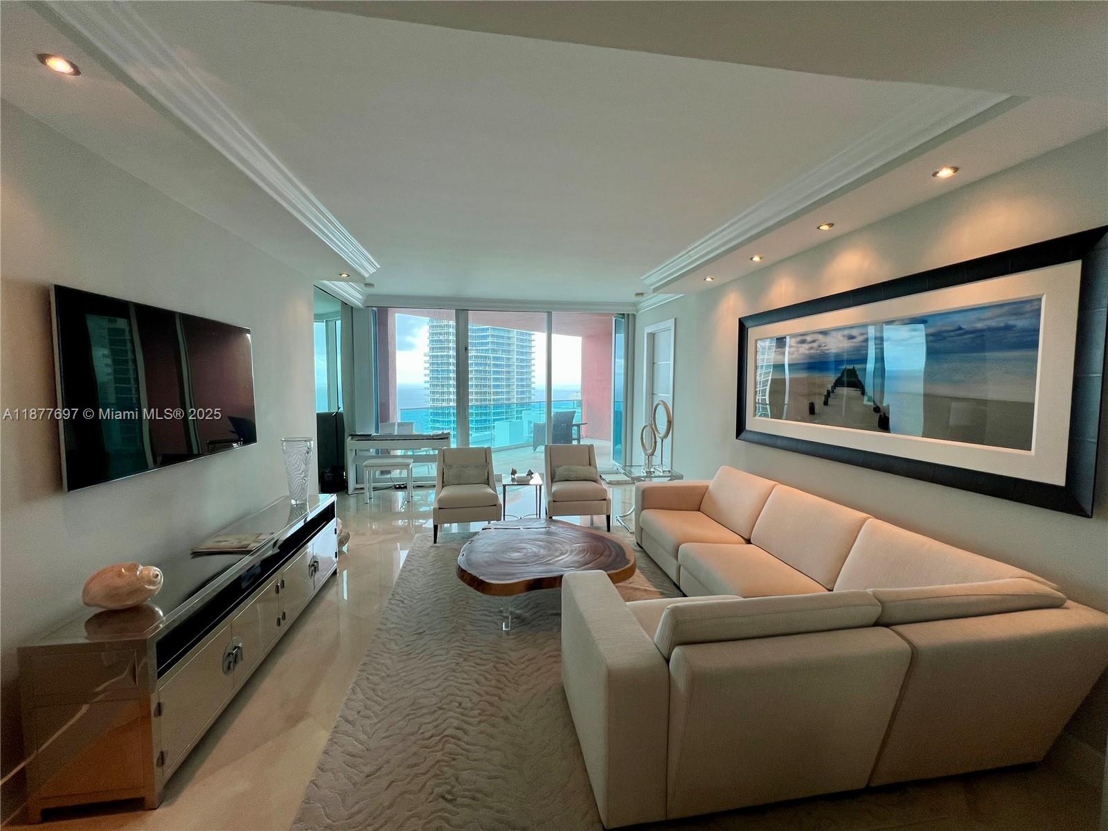 A modern living room features a beige sectional sofa, wood coffee table, and ocean views — 300 S Pointe Dr # 2806, Miami Beach FL 33139, MIAMI BEACH, FL
