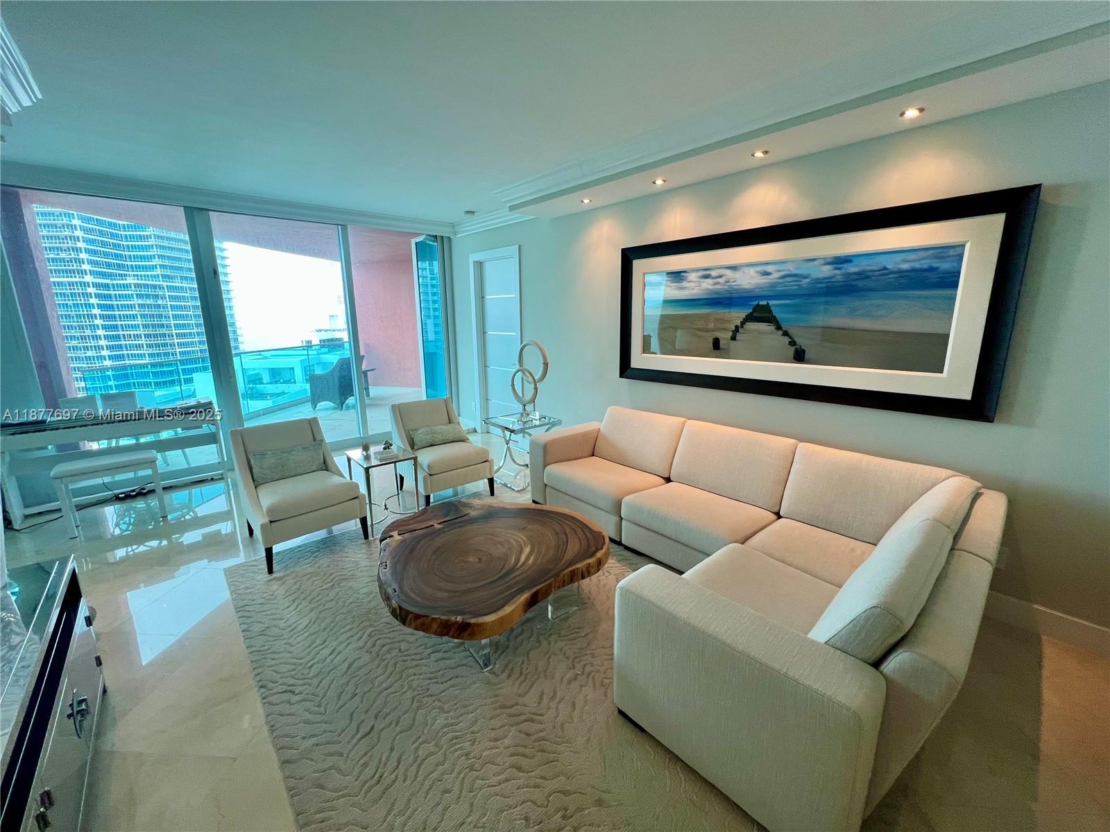 A living room features a sectional sofa, a live-edge coffee table, and a large landscape painting — 300 S Pointe Dr # 2806, Miami Beach FL 33139, MIAMI BEACH, FL