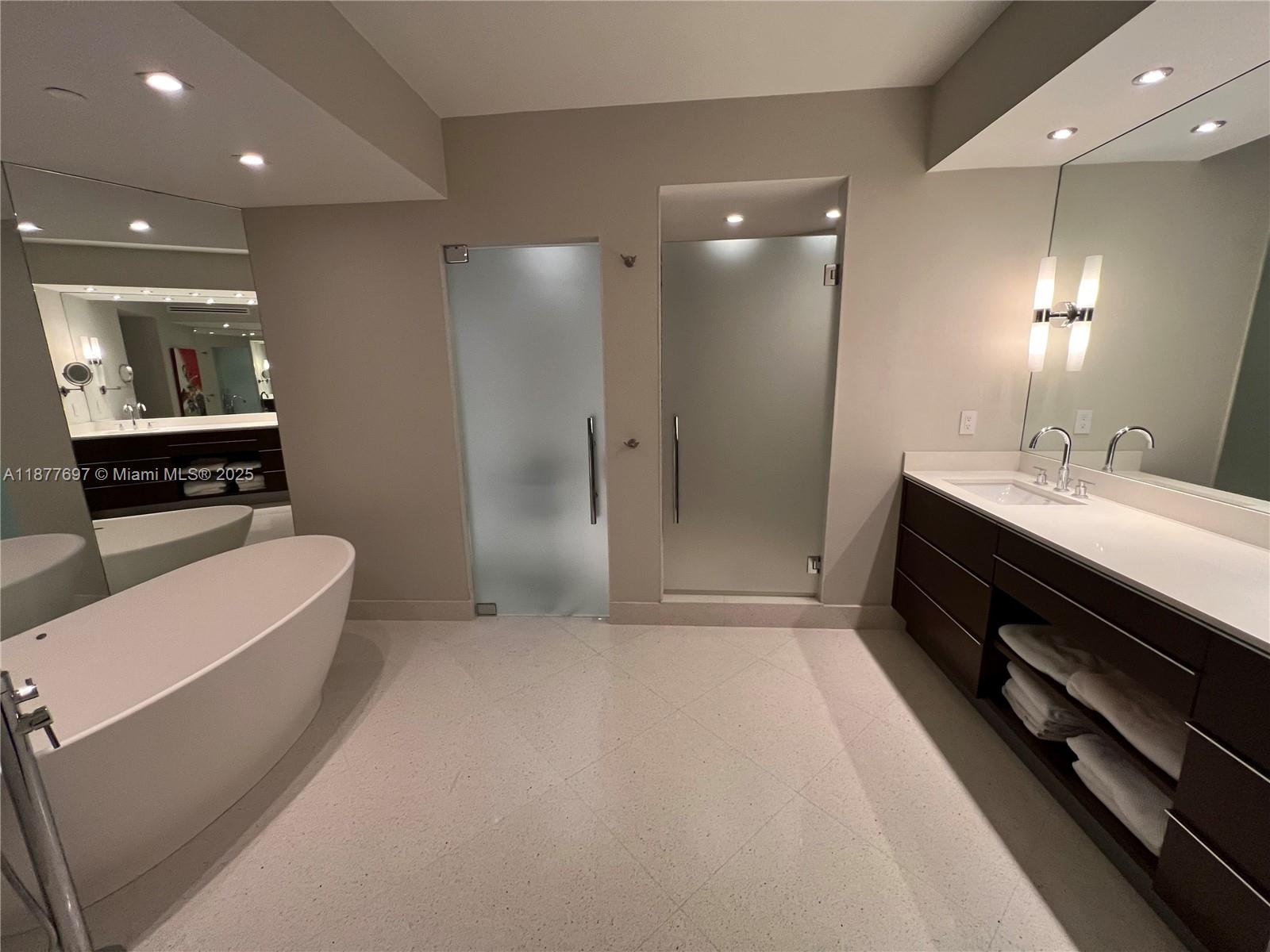 A modern bathroom features a freestanding tub, dual glass-door enclosures, and a dark wood vanity — 300 S Pointe Dr # 2806, Miami Beach FL 33139, MIAMI BEACH, FL