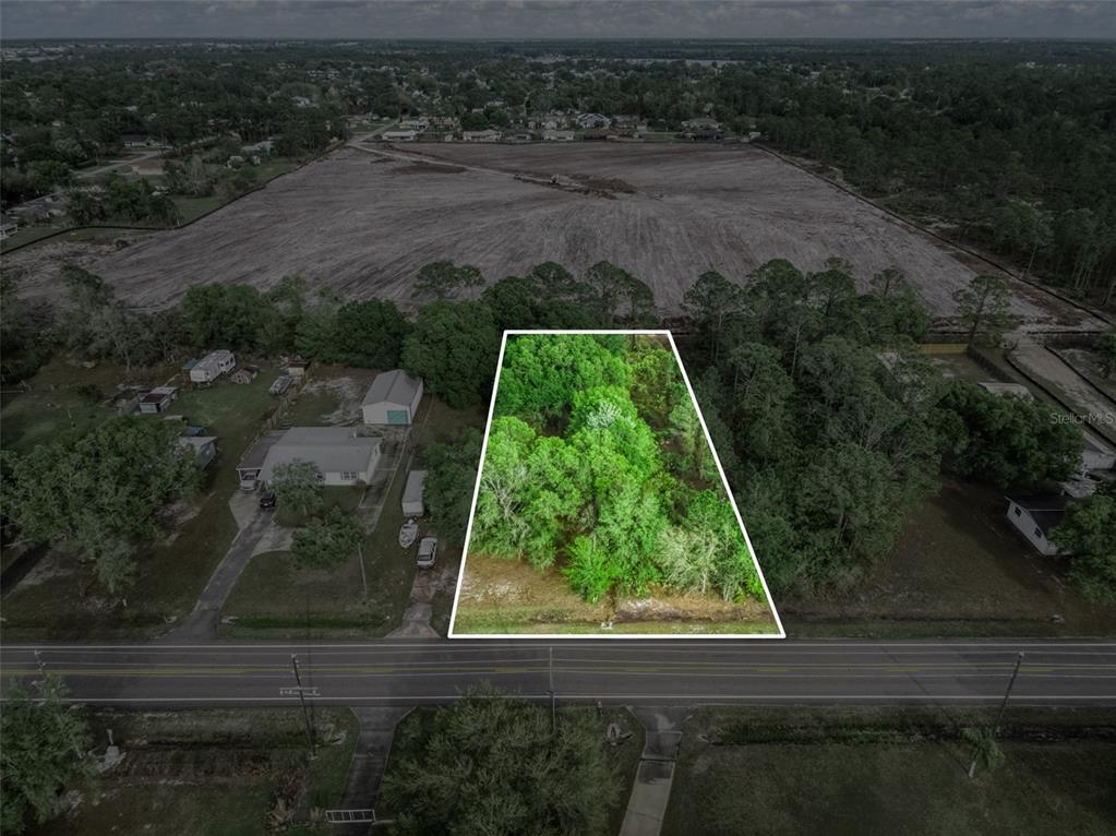 An aerial view shows a wooded, trapezoidal vacant lot bordered by a road and cleared land — 4814 LAKEWOOD ROAD, SEBRING, FL