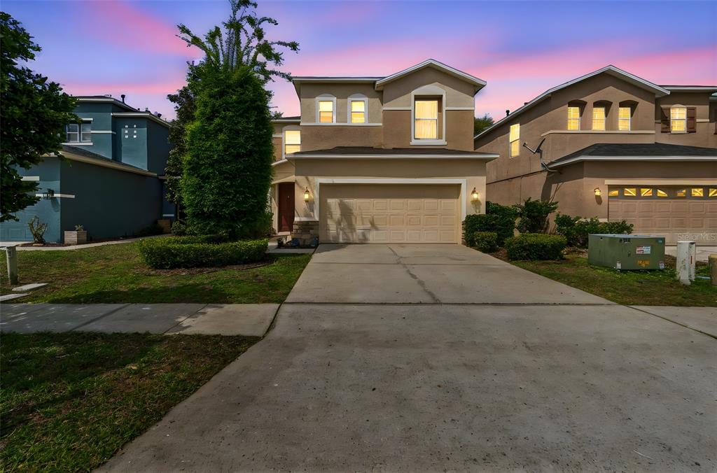 A two-story suburban house with a beige stucco exterior and a two-car garage — 2401 SILVERMOSS DRIVE, WESLEY CHAPEL, FL