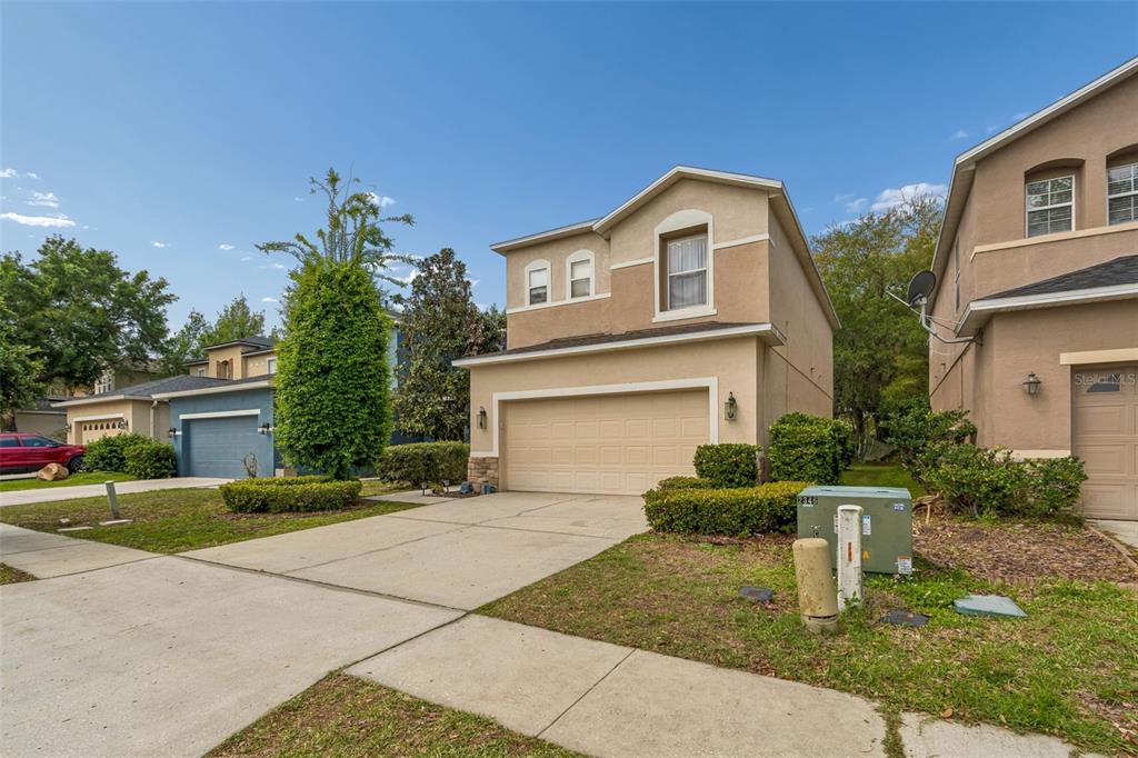 A two-story suburban house with a beige stucco exterior and a two-car garage — 2401 SILVERMOSS DRIVE, WESLEY CHAPEL, FL
