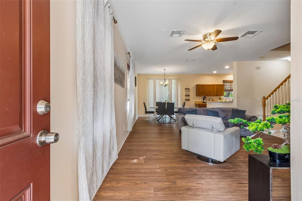 An open-concept living and dining area features wood-look flooring, a ceiling fan, and stairs — 2401 SILVERMOSS DRIVE, WESLEY CHAPEL, FL