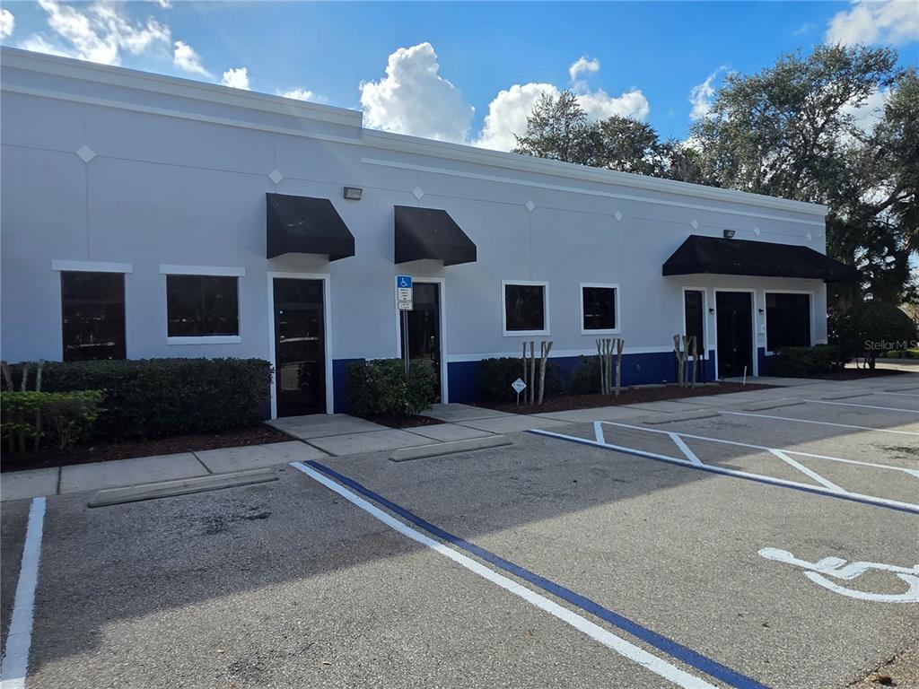 A single-story commercial building with a gray facade, black awnings, and a paved parking lot — 1400 JORDAN AVENUE UNIT 3 & 4, ORLANDO, FL