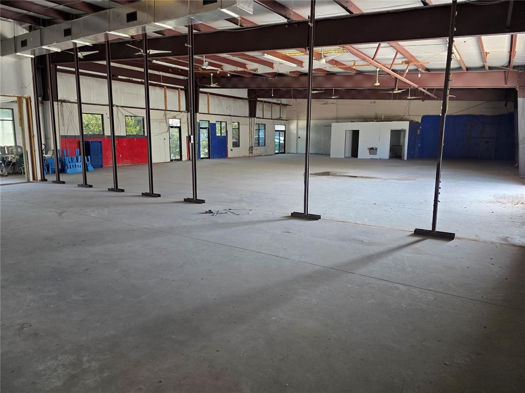 A large, open-concept commercial warehouse space features concrete floors and exposed metal ceiling beams — 1400 JORDAN AVENUE UNIT 3 & 4, ORLANDO, FL