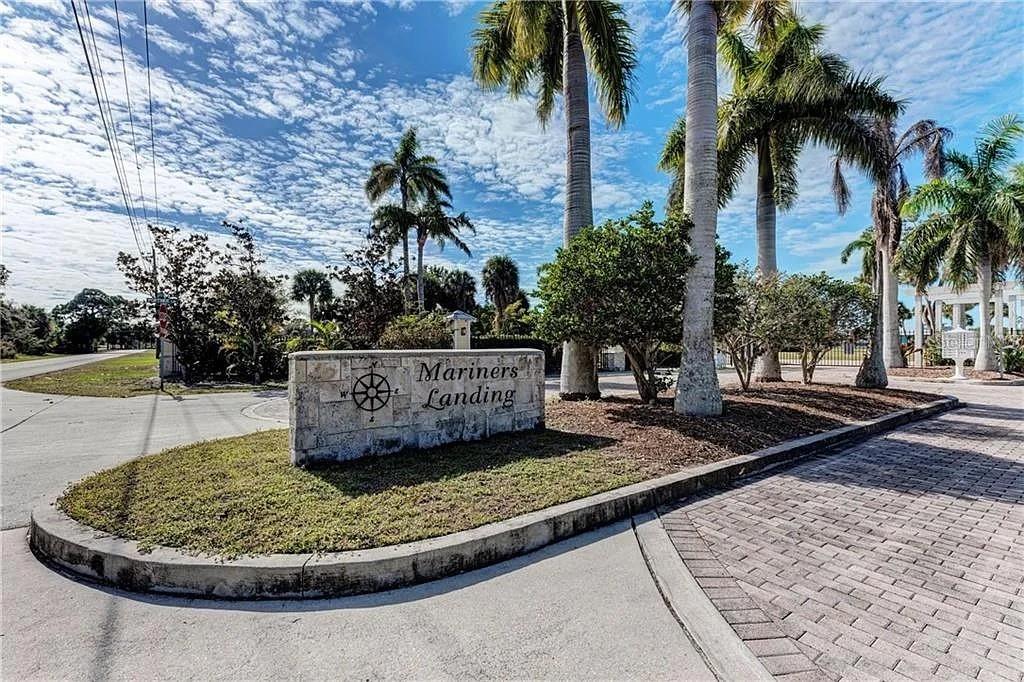 A stone monument sign for Mariners Landing stands at the entrance of a paved community — 6711 PORTSIDE LANE, ENGLEWOOD, FL