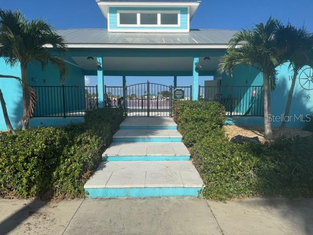 A turquoise building with a metal roof features a gated entrance and stone steps — 6711 PORTSIDE LANE, ENGLEWOOD, FL