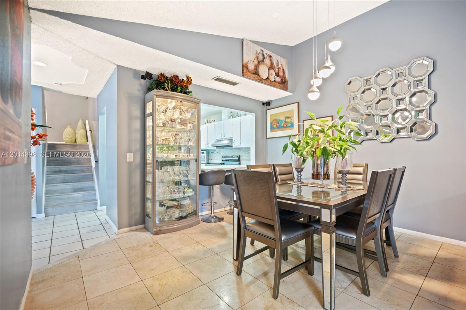 A dining room features a glass-topped table, mirrored accents, a display cabinet, and tiled flooring — 4582 Holly Lake Dr, Lake Worth FL 33463, LAKE WORTH, FL