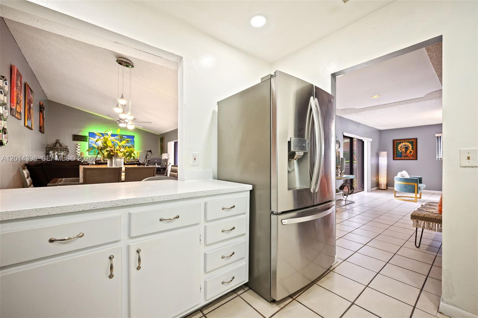 A kitchen features white cabinets, a stainless steel refrigerator, and a pass-through to the dining area — 4582 Holly Lake Dr, Lake Worth FL 33463, LAKE WORTH, FL