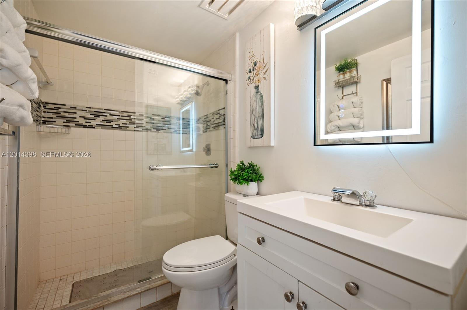 A bathroom features a glass-enclosed shower, a white vanity with a sink, and a mirror — 4582 Holly Lake Dr, Lake Worth FL 33463, LAKE WORTH, FL