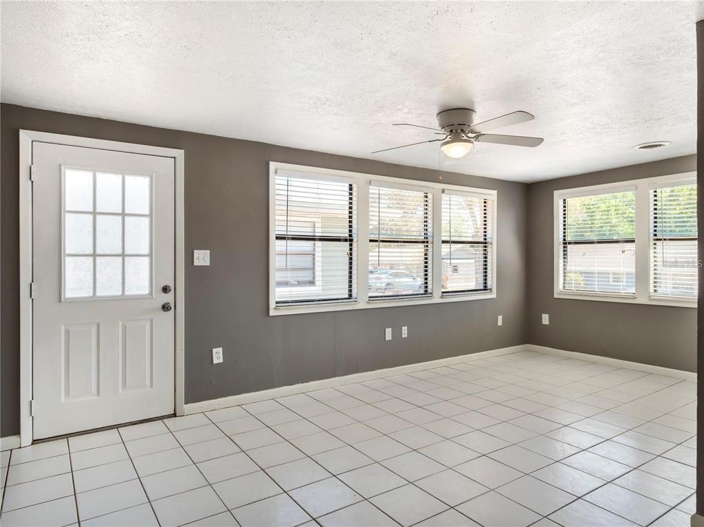 A room with gray walls, white tile flooring, a ceiling fan, and multiple windows — 10301 US HIGHWAY 27 UNIT 172, CLERMONT, FL