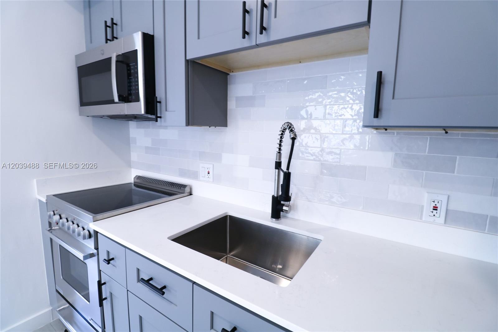A kitchen features gray cabinets, white countertops, a stainless steel sink, and a subway-tile backsplash — 221 SW 11th Ave # 2, Miami FL 33130, MIAMI, FL