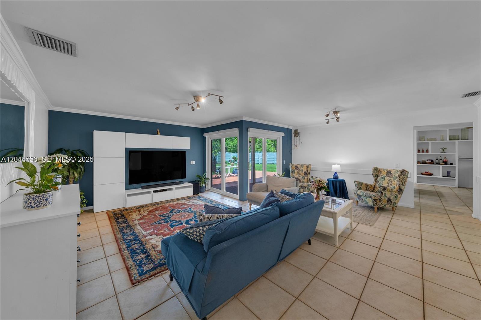 A living room features a blue accent wall, tile flooring, and a large area rug — 14630 SW 147th Ct, Miami FL 33196, MIAMI, FL