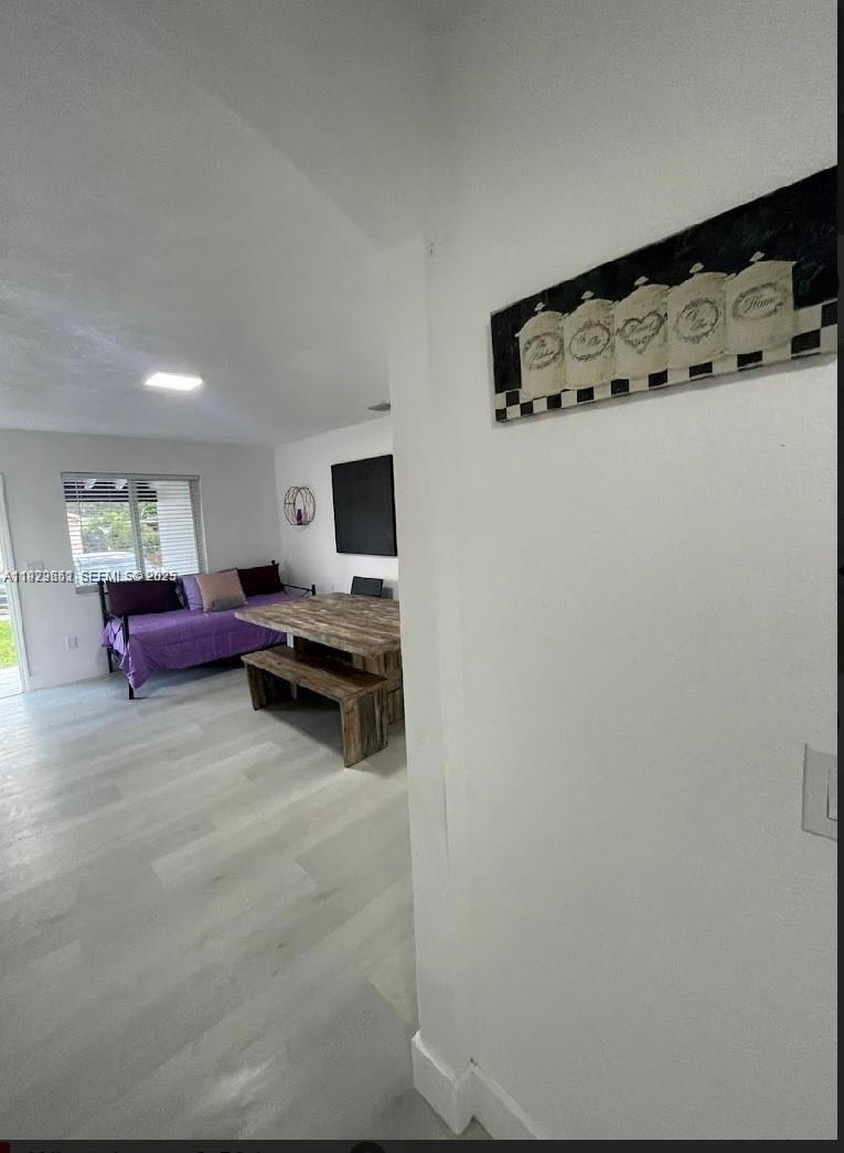 A room with light wood-look flooring features a dining table, a bench, and a daybed — 3085 NW 51st St, Miami FL 33142, MIAMI, FL