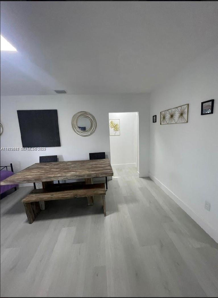 A dining area features a wooden table and bench on light-colored wood-look flooring — 3085 NW 51st St, Miami FL 33142, MIAMI, FL