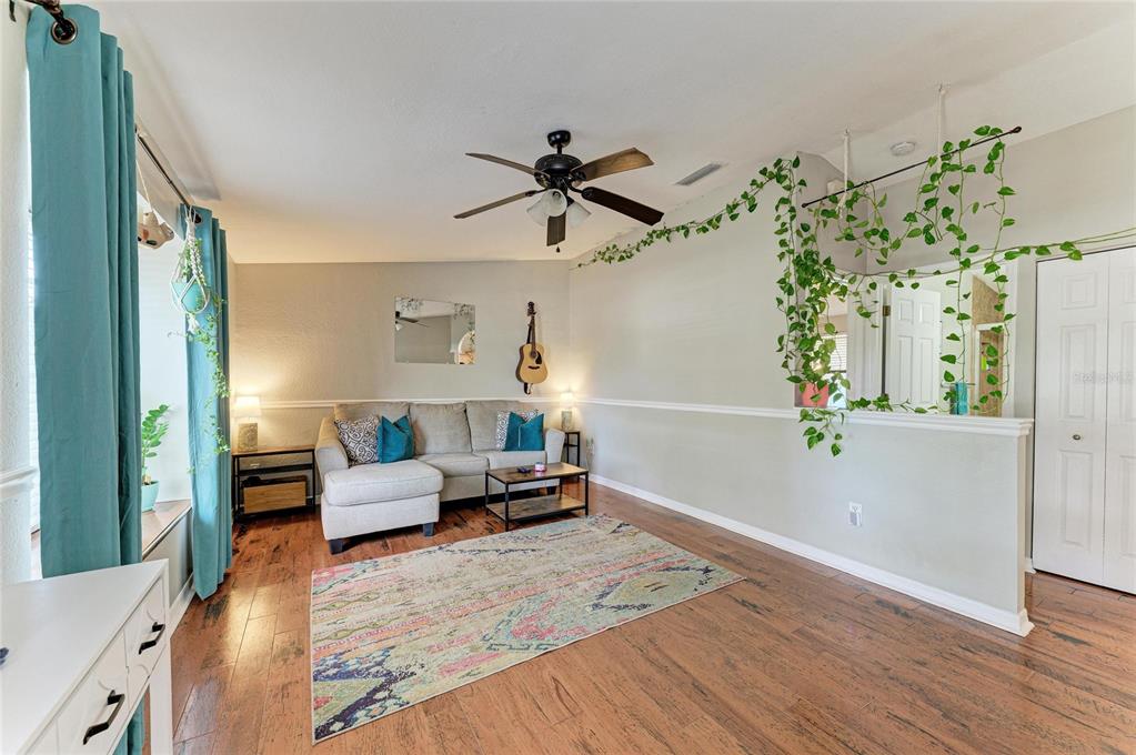 A living room features a sectional sofa, hardwood floors, a ceiling fan, and hanging plants — 2226 LOCKWOOD MEADOWS DRIVE, SARASOTA, FL