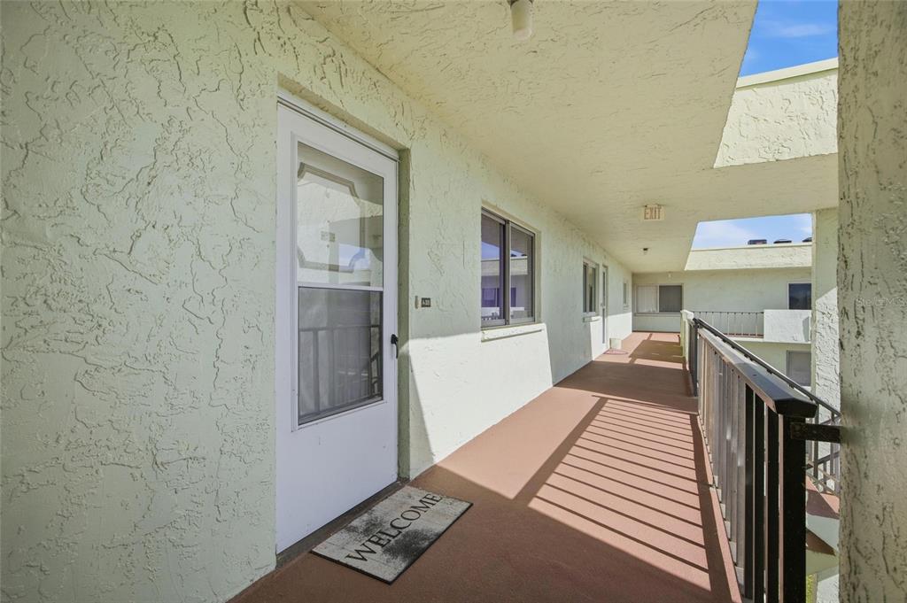 An exterior walkway with a white door, a welcome mat, and a metal railing — 1130 N LAKE PARKER AVENUE UNIT A305, LAKELAND, FL