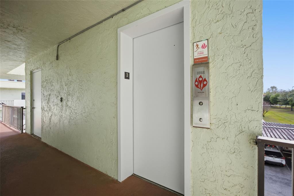 An elevator door with a call button panel is located on an outdoor apartment hallway — 1130 N LAKE PARKER AVENUE UNIT A305, LAKELAND, FL