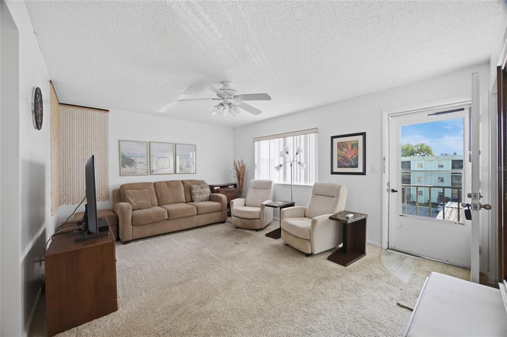 A living room features a beige sofa, two armchairs, carpeted flooring, and a glass door — 1130 N LAKE PARKER AVENUE UNIT A305, LAKELAND, FL