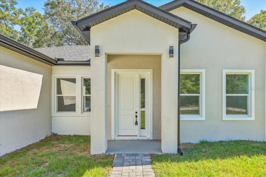 A single-story house with a two-car garage and a paved walkway at sunset — 10611 N UMBER TERRACE, CITRUS SPRINGS, FL