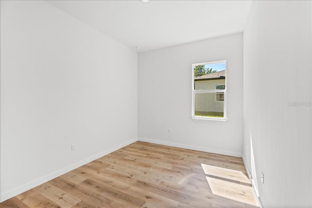 An open-concept living room and kitchen feature wood-look flooring, white cabinetry, and a navy accent wall — 10611 N UMBER TERRACE, CITRUS SPRINGS, FL