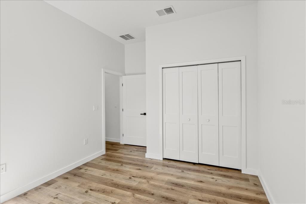 An empty room with white walls, light wood-look flooring, and two windows overlooking trees — 10611 N UMBER TERRACE, CITRUS SPRINGS, FL