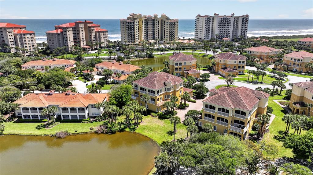 An aerial view shows multi-story residential buildings with orange roofs surrounding a central pond — 40 CASA BELLA CIRCLE UNIT 1101, PALM COAST, FL