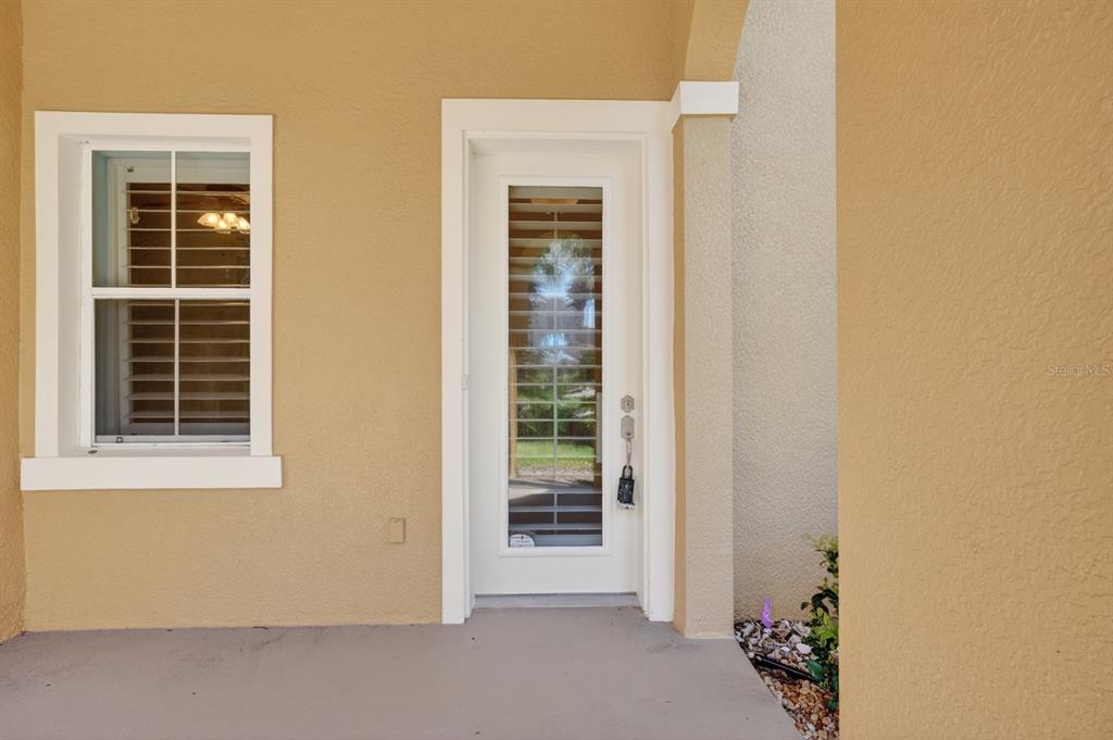 A white door with a glass insert and a window sit on a tan porch — 40 CASA BELLA CIRCLE UNIT 1101, PALM COAST, FL
