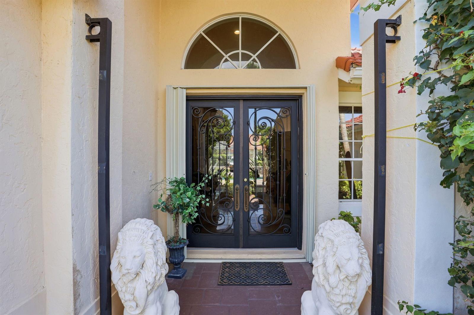 A front entrance features double iron-grille doors flanked by two white stone lion statues — 7821 Dorchester Road, Boynton Beach FL 33472, BOYNTON BEACH, FL