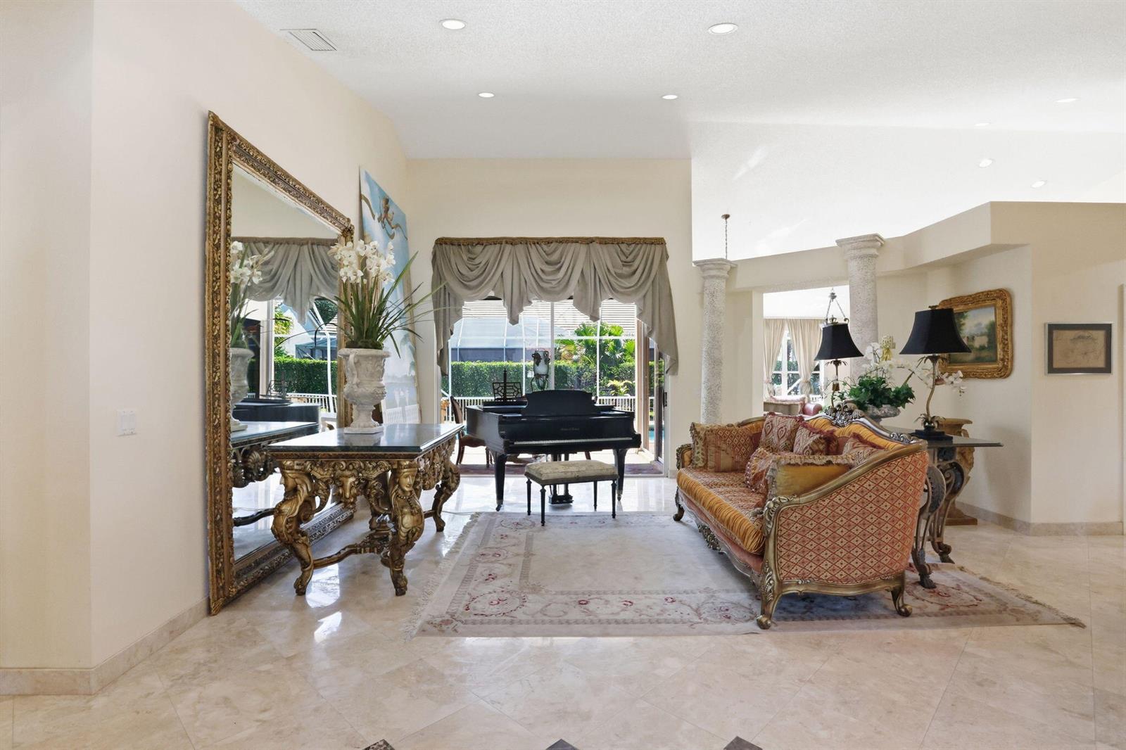 A formal living room features a grand piano, ornate gold furniture, and large sliding glass doors — 7821 Dorchester Road, Boynton Beach FL 33472, BOYNTON BEACH, FL