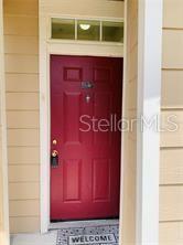 A red front door with a transom window is set within tan horizontal siding — 1980 ERVING CIRCLE UNIT 107, OCOEE, FL