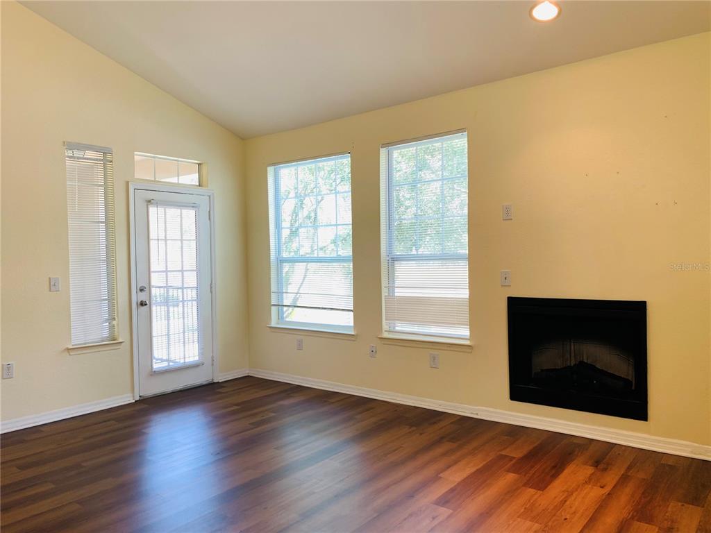 A living room features light yellow walls, dark wood flooring, a fireplace, and a door — 1980 ERVING CIRCLE UNIT 107, OCOEE, FL