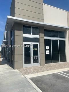 A modern commercial building exterior features a glass-paneled double door entrance and large dark windows — 10890 NW 17 TH ST # 128, Miami 00172, MIAMI, FL