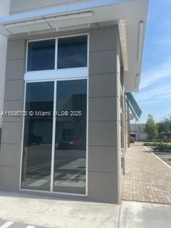 A modern commercial building exterior features large glass windows and gray panel siding — 10890 NW 17 TH ST # 128, Miami 00172, MIAMI, FL