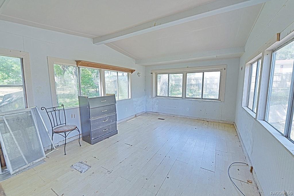 A sunroom with white walls, light-colored wood flooring, and multiple windows overlooking a yard — 5332 E SOUTH CROSSING COURT, INVERNESS, FL